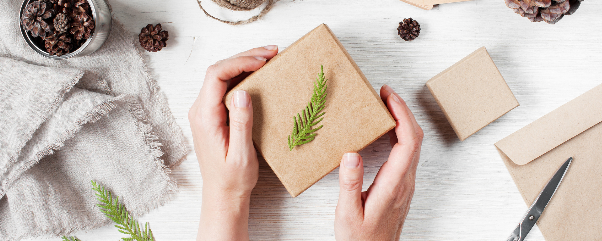 A brown paper wrapped gift box with a green leaf on top