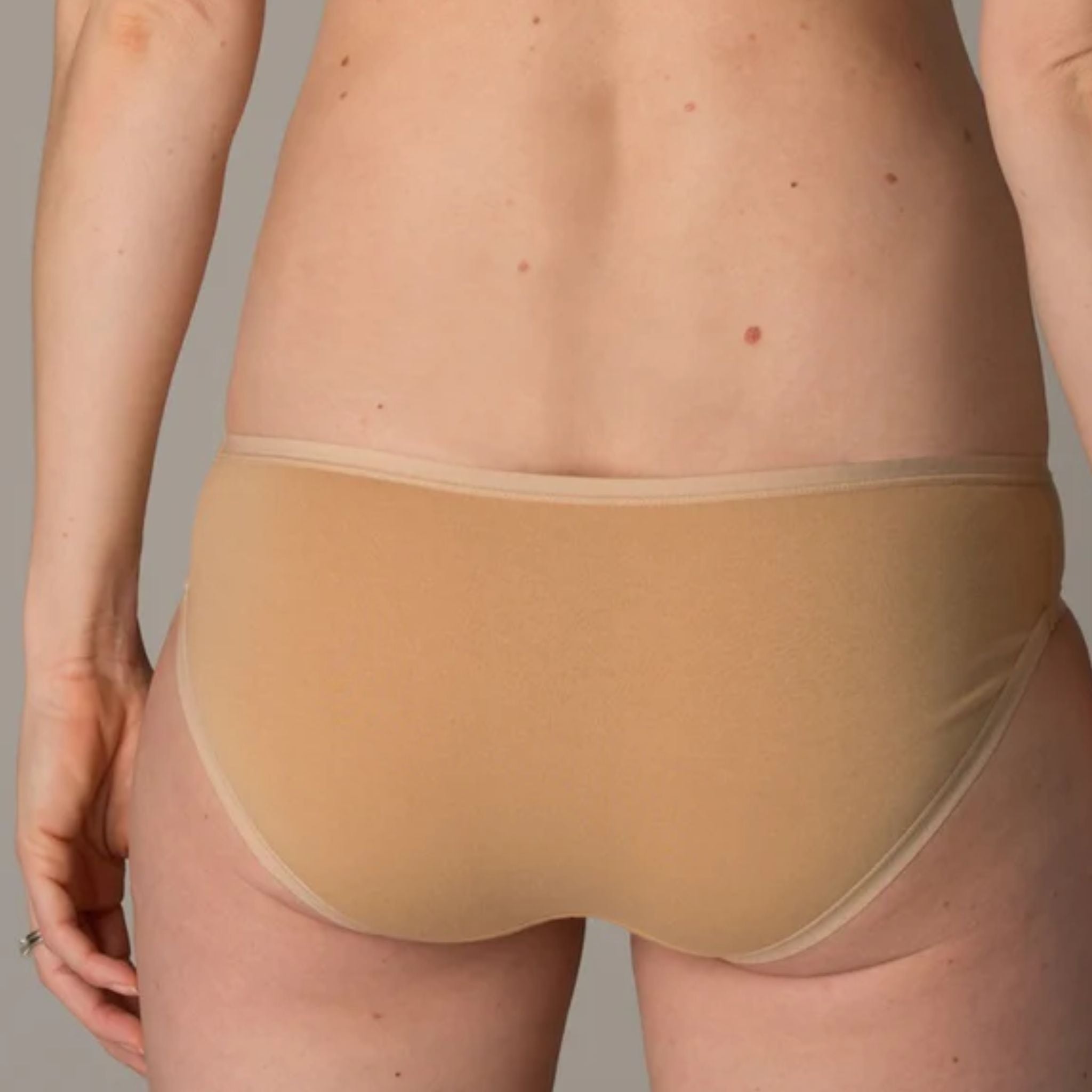 Person wearing almond bikini bottoms, showing back view