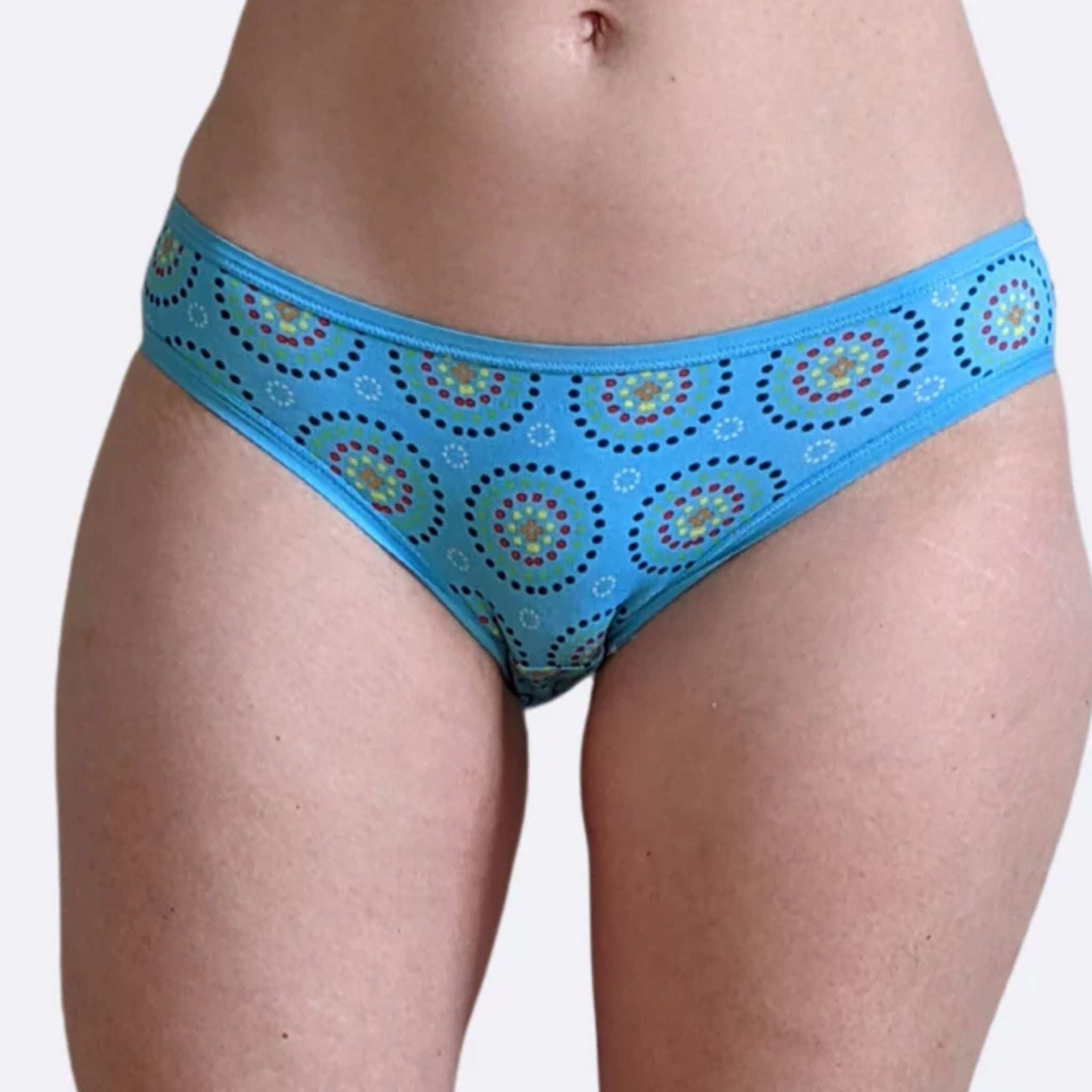 Person wearing blue bikini bottoms with circular patterns, showing the front view